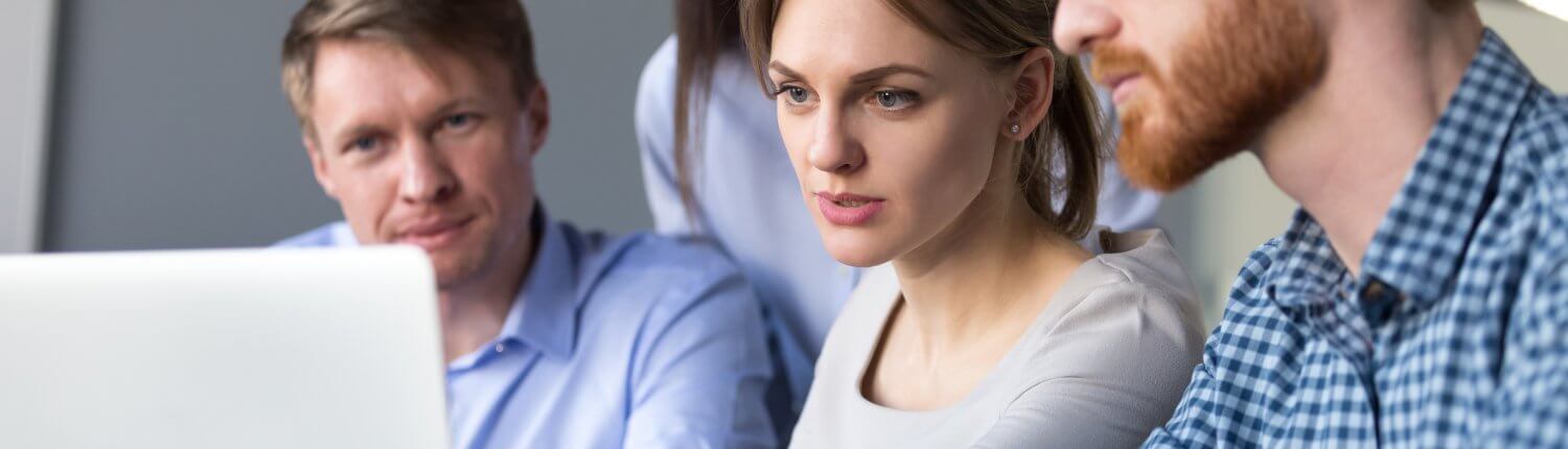 Zwei Frauen und zwei Männer schauen auf einen Monitor